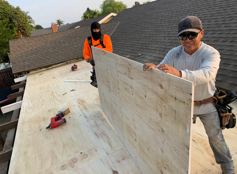 contractors carrying plywood on a roof rancho santa margarita ca
